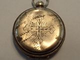 une petite montre de poche en argent ornée d'une croix