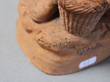 a clay statue of a dog with a basket on its head