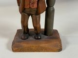 a wooden statue of a man with a hat and a cane