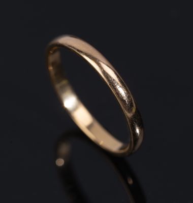 a close up of a gold wedding ring on a black surface