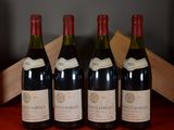 four bottles of wine are lined up on a red table
