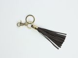 Le porte-clés à pompon en cuir noir est muni d'un anneau métallique plaqué or et d'un pompon en cuir noir