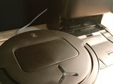 a robotic vacuum sitting on a desk next to a laptop