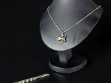 un ensemble composé d'un collier et de boucles d'oreilles posé sur un présentoir à côté d'une paire de boucles d'oreilles