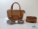 un sac à main et une ceinture posés sur une table, à côté d'une paire de lunettes