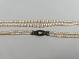 un gros plan sur un collier de perles blanches muni d'un fermoir noir
