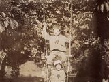 une photo ancienne représentant un jeune garçon sur une balançoire