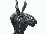 statue of a black goat head with horns on a wooden base