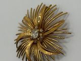 an image of a gold brooch with a diamond in the center