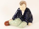 a figurine of a man sitting on the ground