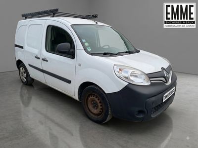 La camionnette blanche est garée dans une grande pièce équipée d'une galerie de toit noire.