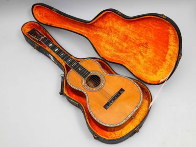 une guitare dans un étui, posée sur une surface blanche, avec un fond blanc