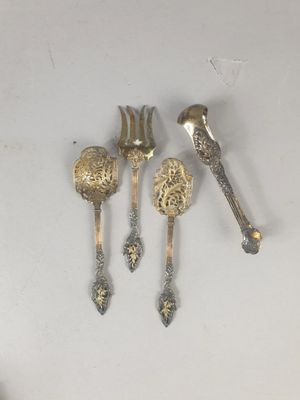 quatre cuillères et une fourchette en argent sur une surface blanche