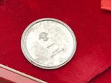 a silver coin in a red box on a blue surface