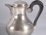 an antique silver tea pot with a bird on the handle