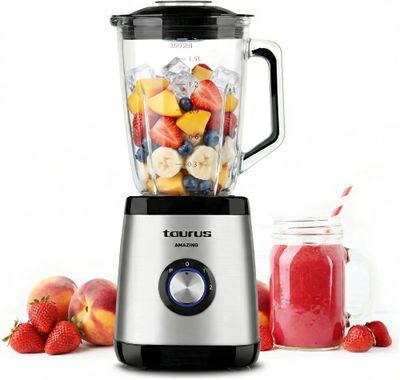 un mixeur contenant des fruits, à côté d'un bocal de smoothie