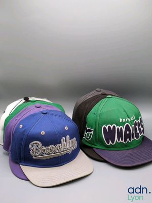 trois casquettes portant les noms d'équipes de baseball, disposées côte à côte
