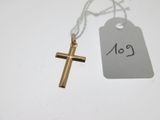 une croix en or et une étiquette de prix posées sur une table blanche