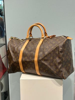 a brown and tan louis vuitton bag sitting on a white pedestal
