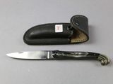 a knife that is laying next to a leather case