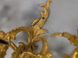 a gold clock that is on the wall next to a vase