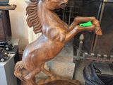 une statue représentant un cheval tenant un frisbee vert dans la bouche
