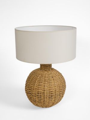 une lampe en rotin surmontée d'un abat-jour blanc