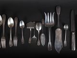 a lot of silver spoons and forks on a black background