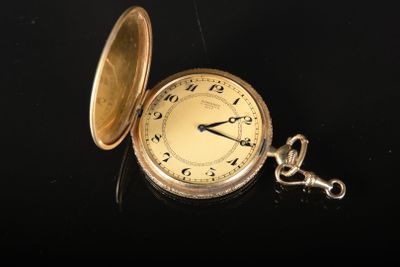 une montre de poche en or posée sur une surface noire