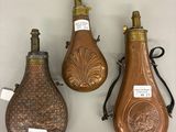 three antique brass bottle shaped vases on display on a white surface
