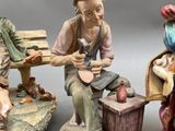 three figurines of people sitting on a bench