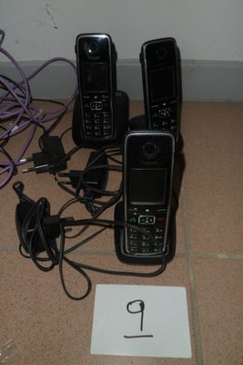 trois téléphones portables posés par terre à côté d'un numéro