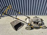a lawn mower that is sitting on the ground next to a trash can