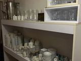 many dishes and cups on the shelves in the kitchen