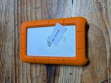 un disque dur orange posé sur une table en bois