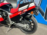 une moto rouge et noire garée devant un mur recouvert de graffitis