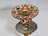 a gold candle holder with a red and blue design on it