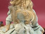 a doll that is sitting on the ground next to a teddy bear