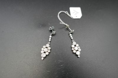une paire de boucles d'oreilles ornées de pierres blanches sur un fond noir