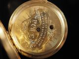 a close up of a gold pocket watch on a black surface