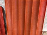 un panneau de toiture ondulé orange à côté d'un mur en briques