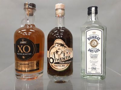 Trois bouteilles d'alcool sont alignées sur une table en verre