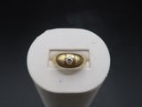 a close up of a white light bulb with a gold button