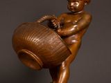 a bronze statue of a boy holding a basket on a wooden base