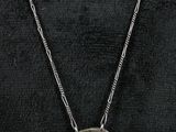 a woman wearing a black shirt and a silver necklace with a long chain