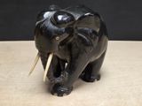 statue of an elephant with tusks on a wooden table