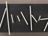 a close up of a black board with white sticks on it