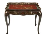 une petite table avec un plateau rouge et des pieds noirs