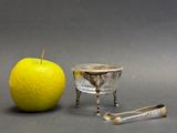 an apple next to a silver cup and a spoon