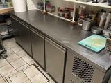stainless steel counter top in a commercial kitchen with lots of dishes on shelves